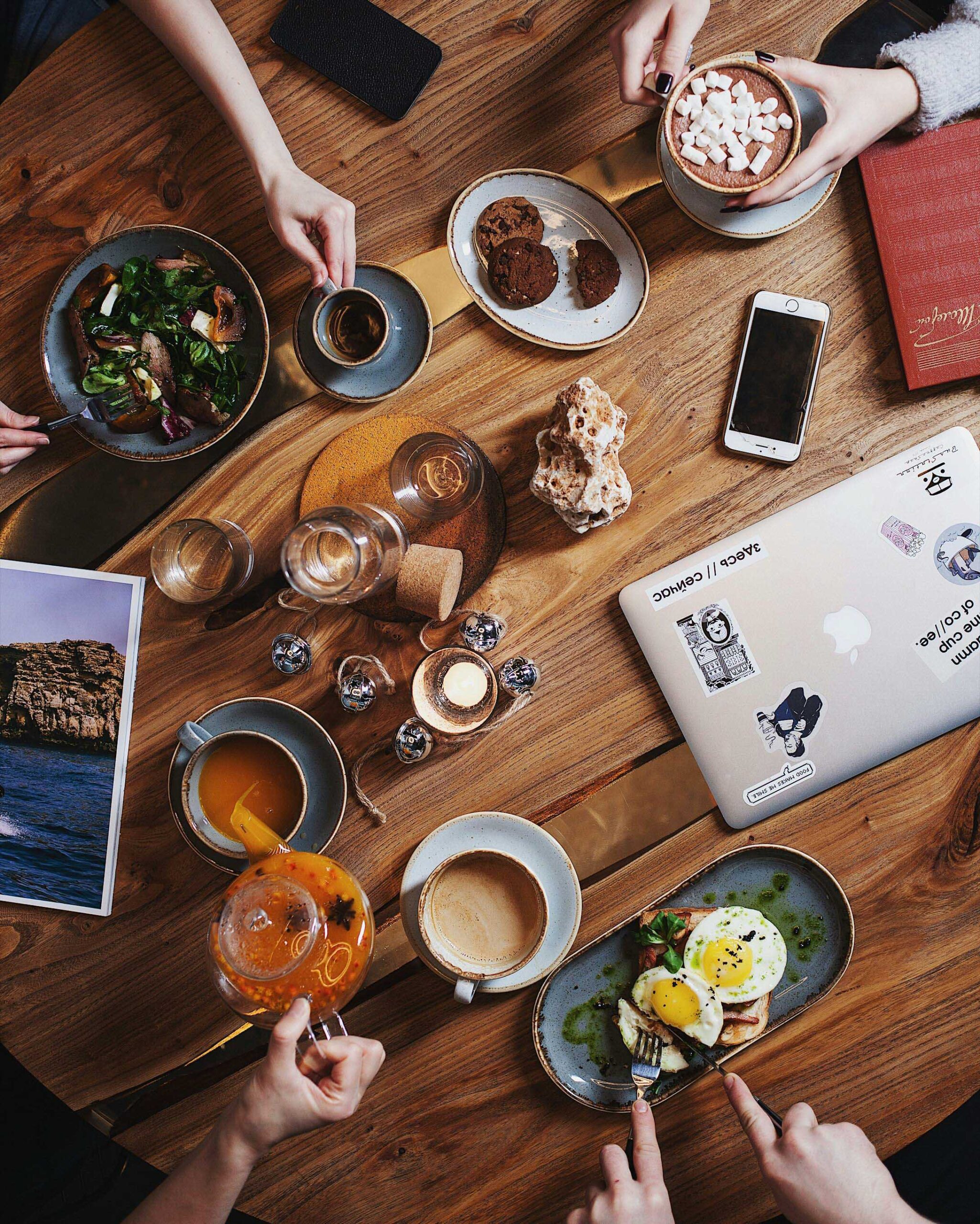 People enjoying coffee and brunch, sitting around a computer and travel photos, planning a trip