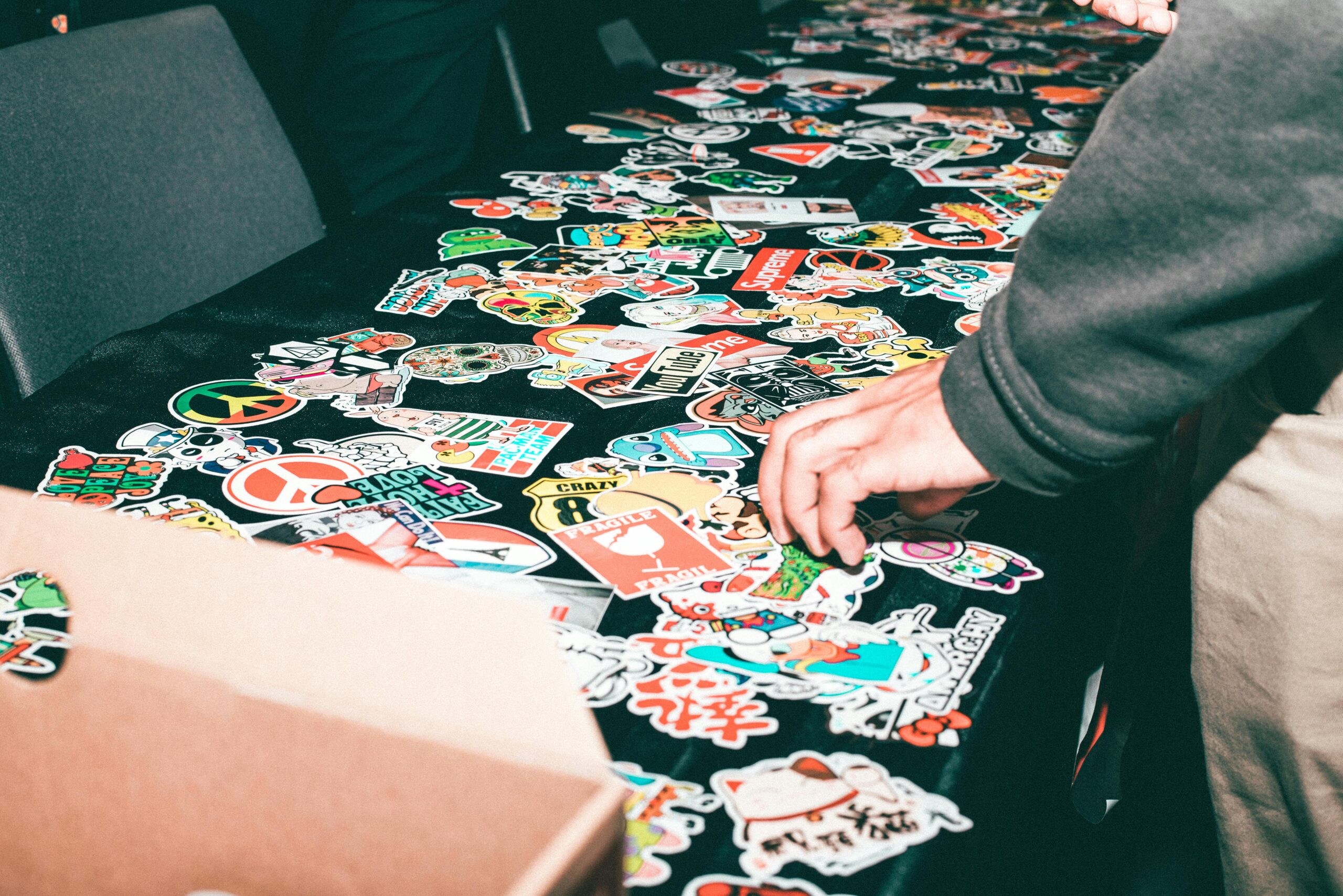 Stickers of different kinds are displayed on a table with a hand reaching for one