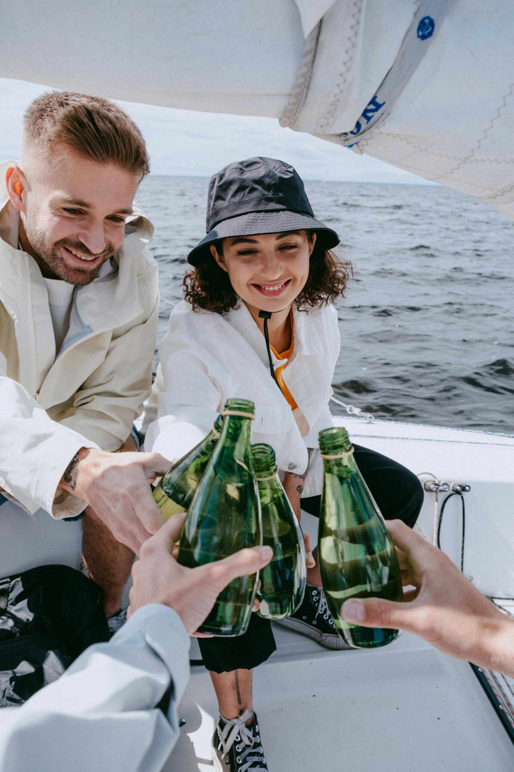 A group of friends on a boat cheers green glass bottles of water