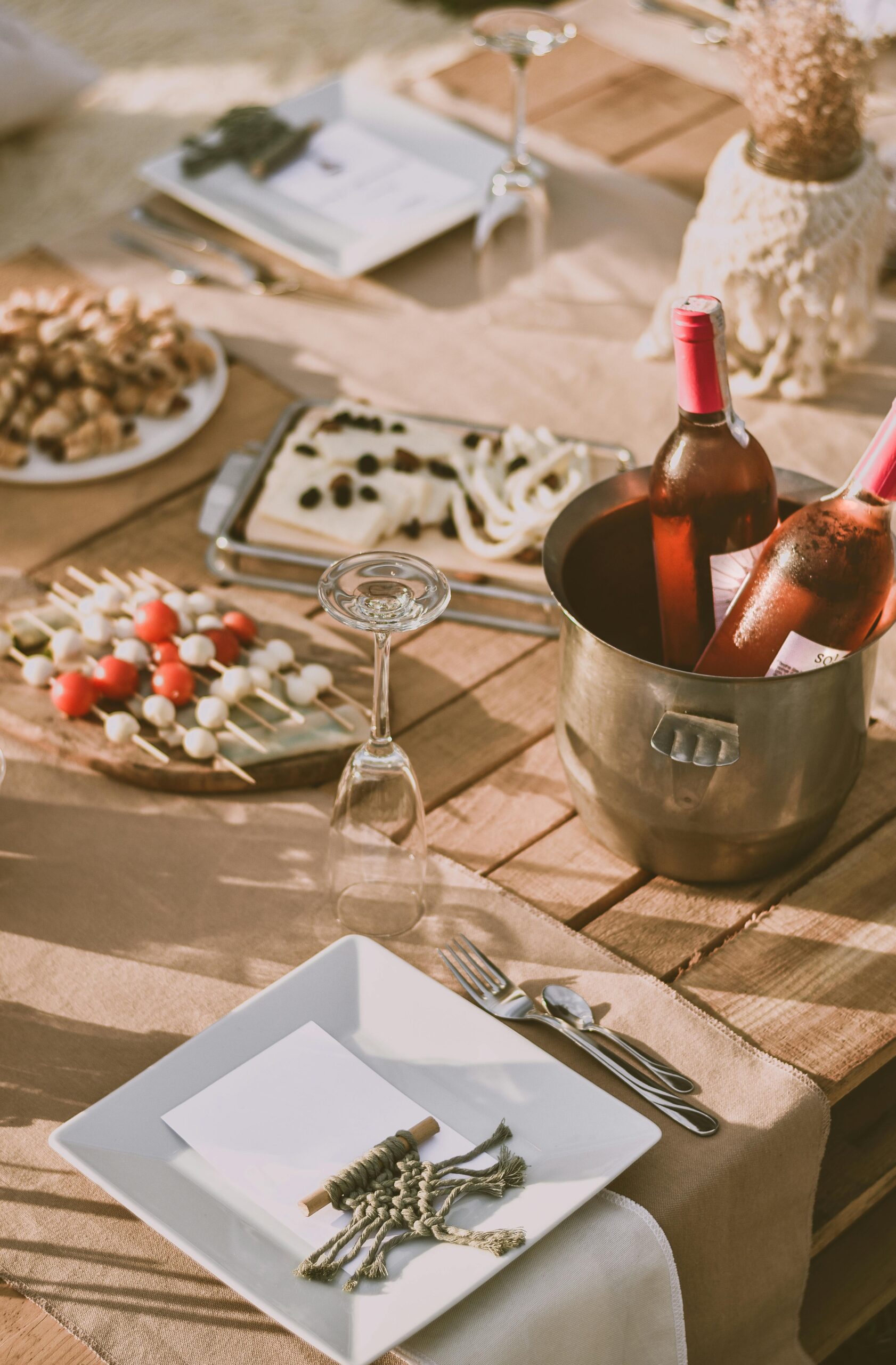 A picnic spread features two bottles of rose wine in an ice bucket